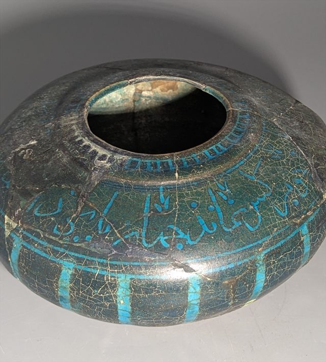 A Kashan turquoise and black glazed vessel, inscribed in Kufic script